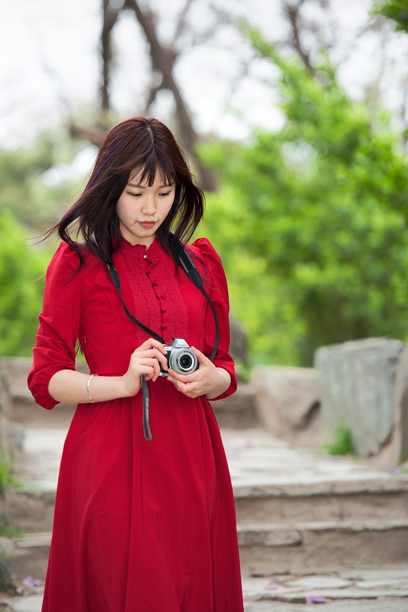 用相机摆拍的红衣女孩